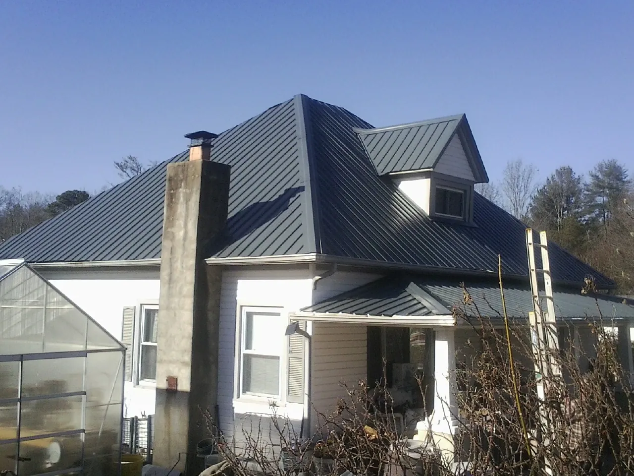 Dark blue standing seam metal roof on a white farmhouse with dormer — Slate & Tile Roof Repair by Roofing Brothers in Gloucester