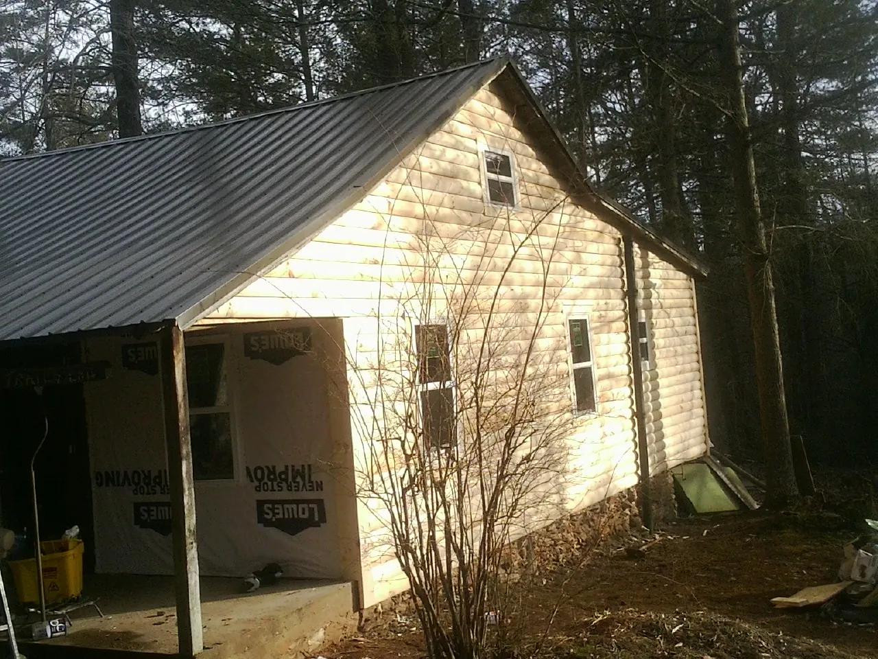 Log siding gable end under a dark metal roof edge in Gloucester