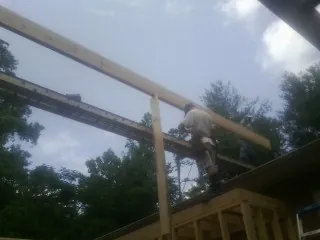 Carpenter setting a ridge beam over a new addition frame — Ice Dam Removal by Roofing Brothers in Gloucester